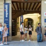 スペインバレンシアのスペイン語学校エスパニョレの正面入口で話している7人の学生