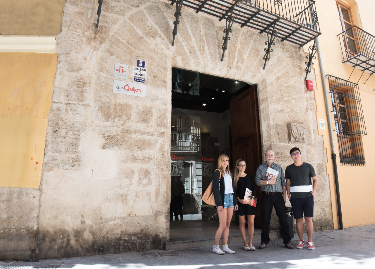 バレンシアのスペイン語スクール、ドン・キホーテの正面入口前でポーズをとる3人の生徒と1人の教師