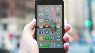 手に持って、画面が正面に見えているスマホ