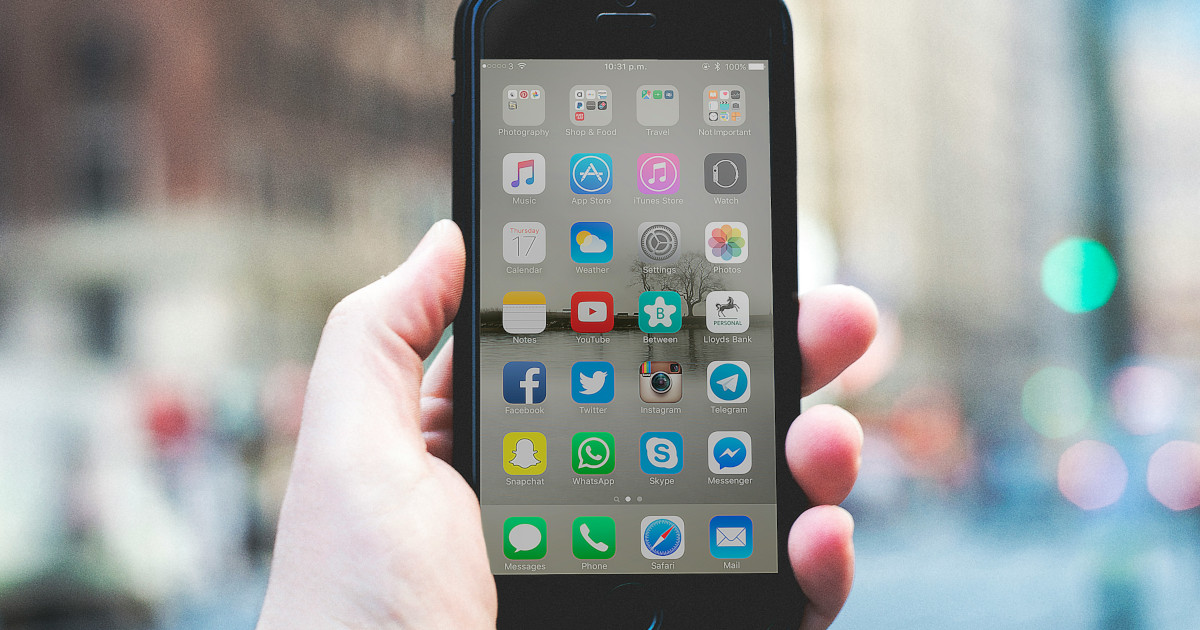 手に持って、画面が正面に見えているスマホ